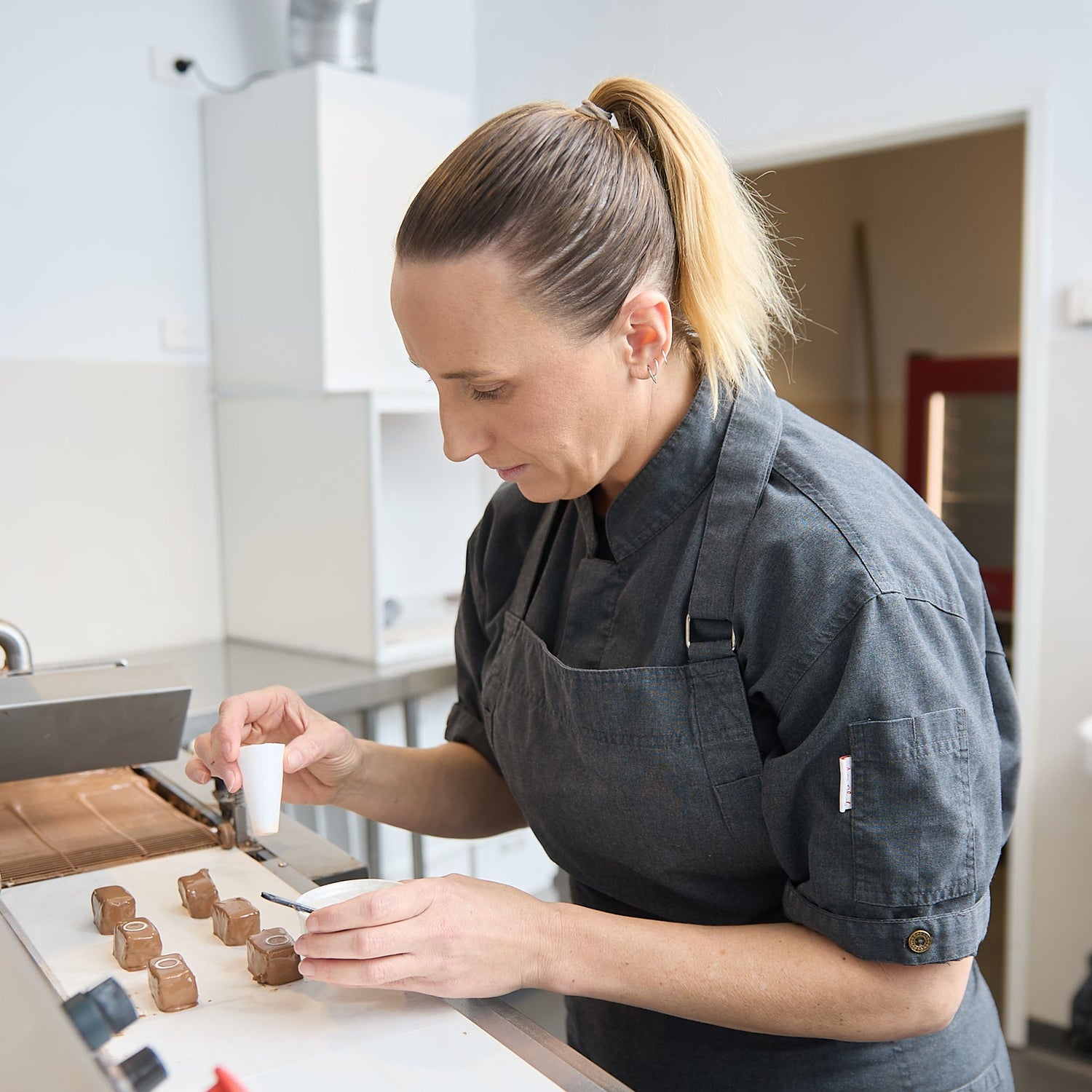 Chocolatier enrobing marshallow in milk chocolate