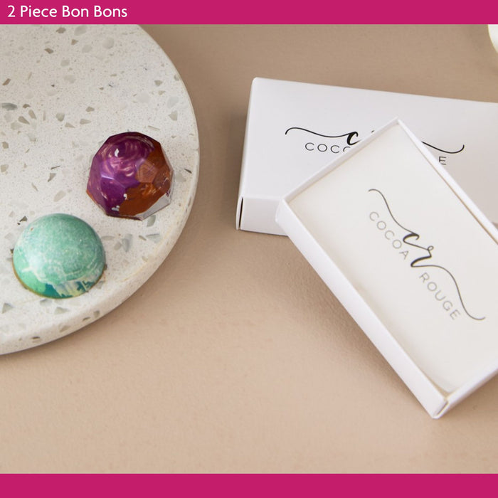 Two-piece bonbons in white boxes with 'Cocoa & Rouge' branding on a beige surface.