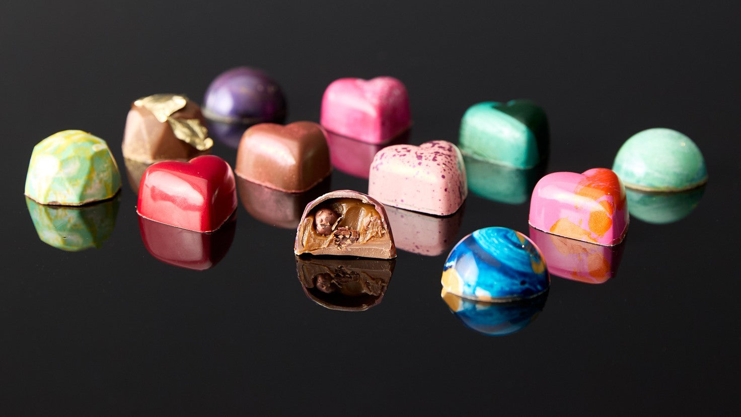 Assorted colorful chocolates on a black reflective surface