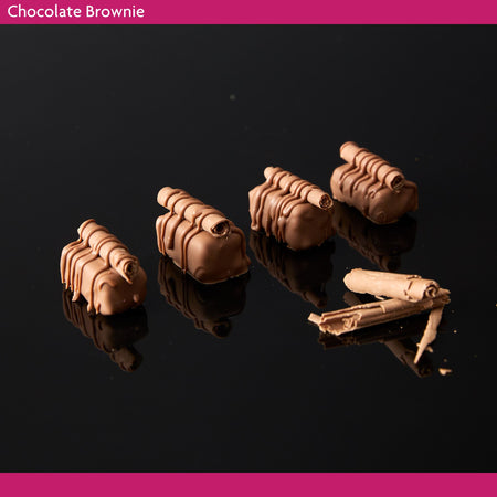 Chocolate brownie pieces covered in milk chocolate on a reflective black surface