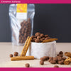 Cinnamon sultanas in milk chocolate with cinnamon sticks on a marble surface against a dark background
