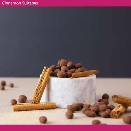 Cinnamon sultanas in a marble bowl with cinnamon sticks on a dark background