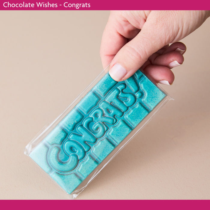 Turquoise chocolate bar with 'Congrats' text held by a hand against a beige background