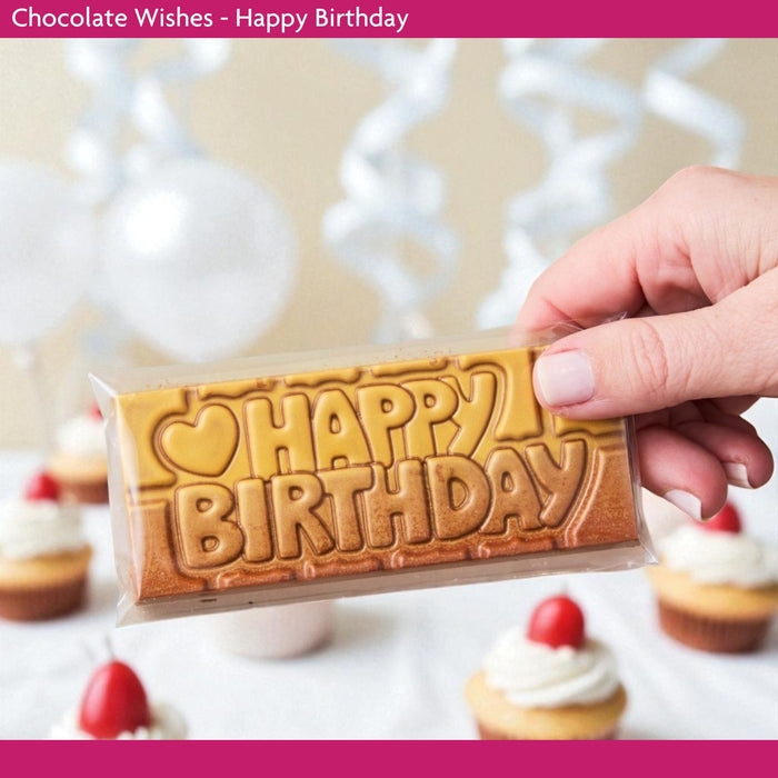 Chocolate bar with 'Happy Birthday' text held by a hand, surrounded by cupcakes.