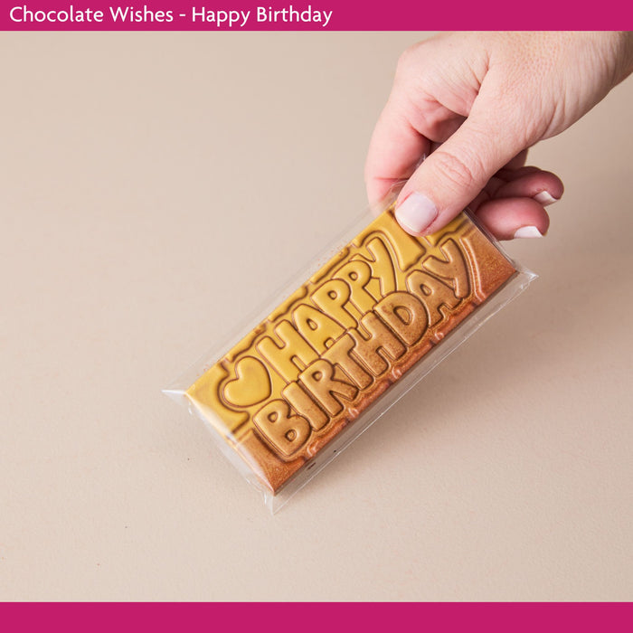 Chocolate bar with 'Happy Birthday' text held by a hand on a beige background