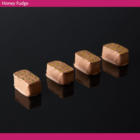 Four pieces of honey fudge on a black reflective surface 