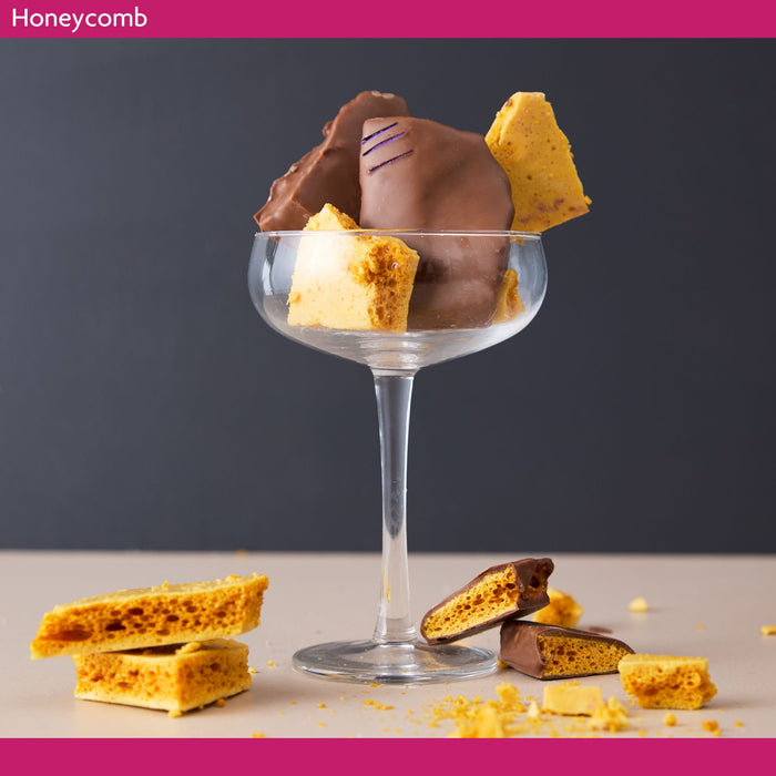Glass dish with chocolate-dipped honeycomb on a dark background