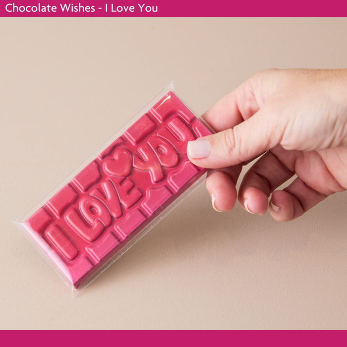 Pink chocolate bar with 'I Love You' text held by a hand on a beige background