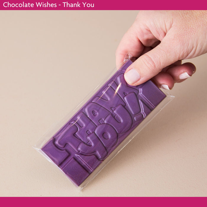 Purple chocolate bar with 'Thank you!' text held by a hand on a beige background