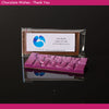 Chocolate bar with 'Thank You' text and a business card on a reflective surface