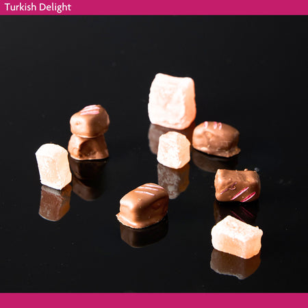 Turkish Delight pieces on a black background coated in milk chocolate